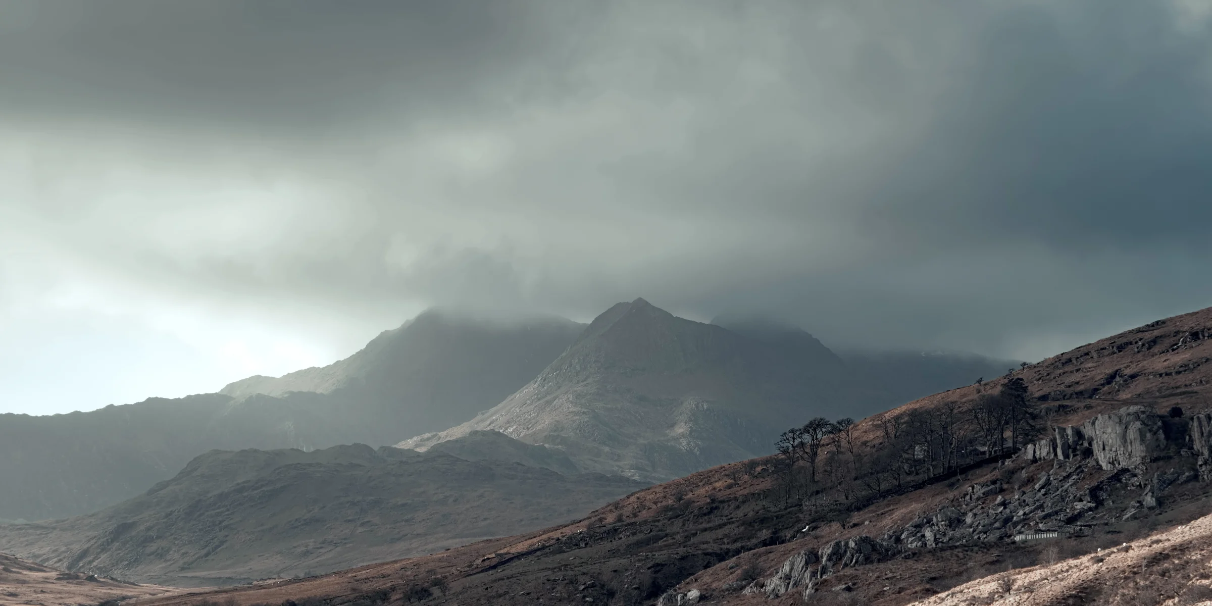 There's a strong chance this image contains the following subjects: landscape,  travel,  nature,  wales,  snowdonia,  eryri,  eryrinationalpark,  nationalpark,  snowdon. The photographer has provided the following description: Snowdon in the clouds last Winter. Taken from Capel Curig, Wales. Photographer_name: Chris Michael. Title: Snowdonia. The photographer has provided the following description: Snowdon in the clouds last Winter. Taken from Capel Curig, Wales. Make: fujifilm. Model: X-T5. Technical: 55-200mm. Published: 2025-09-09 14:05:52