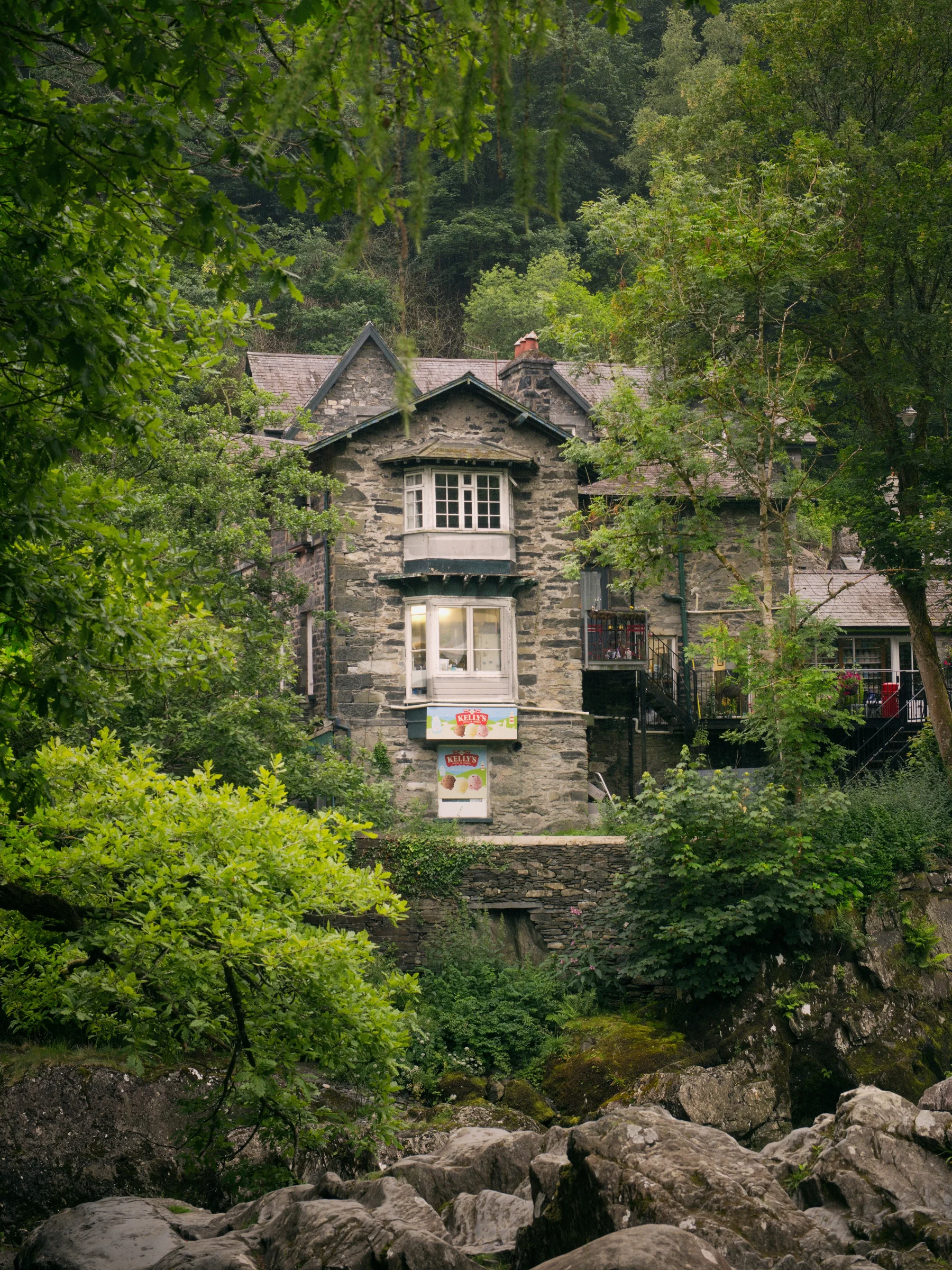 There's a strong chance this image contains the following subjects: architecture,  trees,  wales,  snowdonia,  eryri,  eryrinationalpark,  nationalpark. The photographer has provided the following description: Across the road from the 'falls' is the back of this fish and chip shop (and they sell great ice creams too!). Taken in the beautiful town of Betws-y-Coed. Photographer_name: Chris Michael. Title: Betws-y-Coed. The photographer has provided the following description: Across the road from the 'falls' is the back of this fish and chip shop (and they sell great ice creams too!). Taken in the beautiful town of Betws-y-Coed. Make: fujifilm. Model: X-T5. Technical: 16-80mm. Published: 2025-09-09 14:02:51