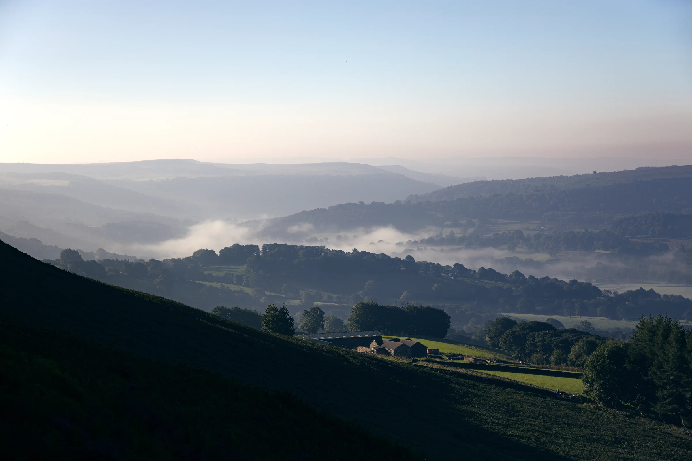 There's a strong chance this image contains the following subjects: sky,  fog,  landscape,  travel,  sunset,  nature,  wood,  dawn,  peakdistrict. The photographer has provided the following description: From up on Bamford Edge, looking down on the village of Hathersage in the Peak District. Photographer_name: Chris Michael. Title: Hathersage. The photographer has provided the following description: From up on Bamford Edge, looking down on the village of Hathersage in the Peak District. Make: canon. Model: Canon EOS R. Technical: Canon RF 70-200mm. Published: 2025-09-05 18:56:14