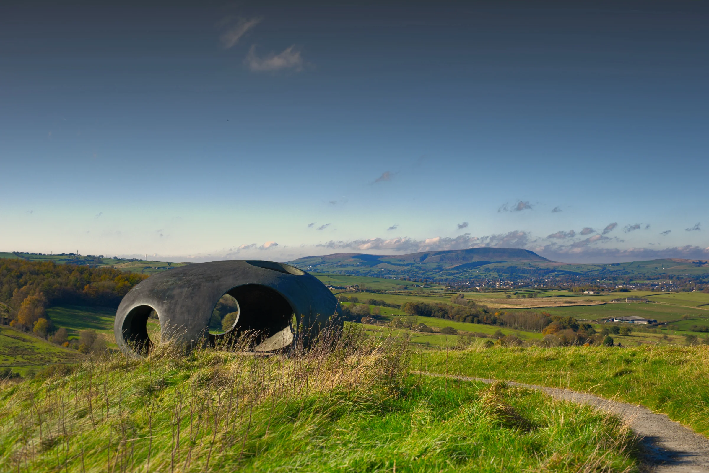 There's a strong chance this image contains the following subjects: sky,  landscape,  travel,  sunset,  nature,  lancashire,  grass. The photographer has provided the following description: This is The Atom panopticon. One of three great sculptures in the area. This is located in Colne, Lancashire. Pendle Hill is seen in the distance. Photographer_name: Chris Michael. Title: The Atom. The photographer has provided the following description: This is The Atom panopticon. One of three great sculptures in the area. This is located in Colne, Lancashire. Pendle Hill is seen in the distance. Make: fujifilm. Model: X-T5. Technical: 16-80mm lens.. Published: 2025-09-06 18:26:58