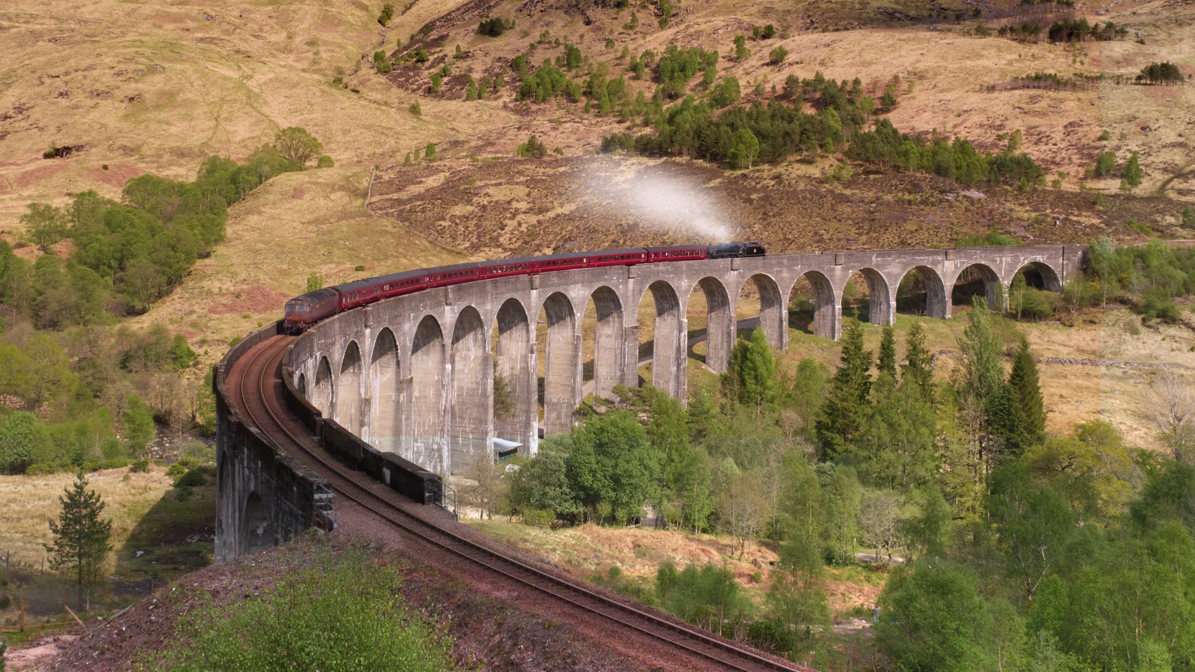 There's a strong chance this image contains the following subjects: landscape,  travel,  nature,  river,  bridge,  scotland,  highlands,  scottishhighlands,  locomotive. The photographer has provided the following description: Also known as the bridge from the Harry Potter movie. Sadly this place is rammed full of tourists now to the point where locals can't cope with the amount of traffic and crazy parking around there. You wouldn't know it, but I was stood amongst a couple of hundred people on this hillside ready to capture this shot. This is the Jacobite steam train from Fort William to Mallaig and only runs a couple of times a day. To get to this viewpoint you need to hike pretty high up if coming from the cute little train station below. Photographer_name: Chris Michael. Title: Glenfinnan Viaduct. The photographer has provided the following description: Also known as the bridge from the Harry Potter movie. Sadly this place is rammed full of tourists now to the point where locals can't cope with the amount of traffic and crazy parking around there. You wouldn't know it, but I was stood amongst a couple of hundred people on this hillside ready to capture this shot. This is the Jacobite steam train from Fort William to Mallaig and only runs a couple of times a day. To get to this viewpoint you need to hike pretty high up if coming from the cute little train station below. Make: fujifilm. Model: X-T5. Technical: 16-80mm. Published: 2025-09-08 21:11:13
