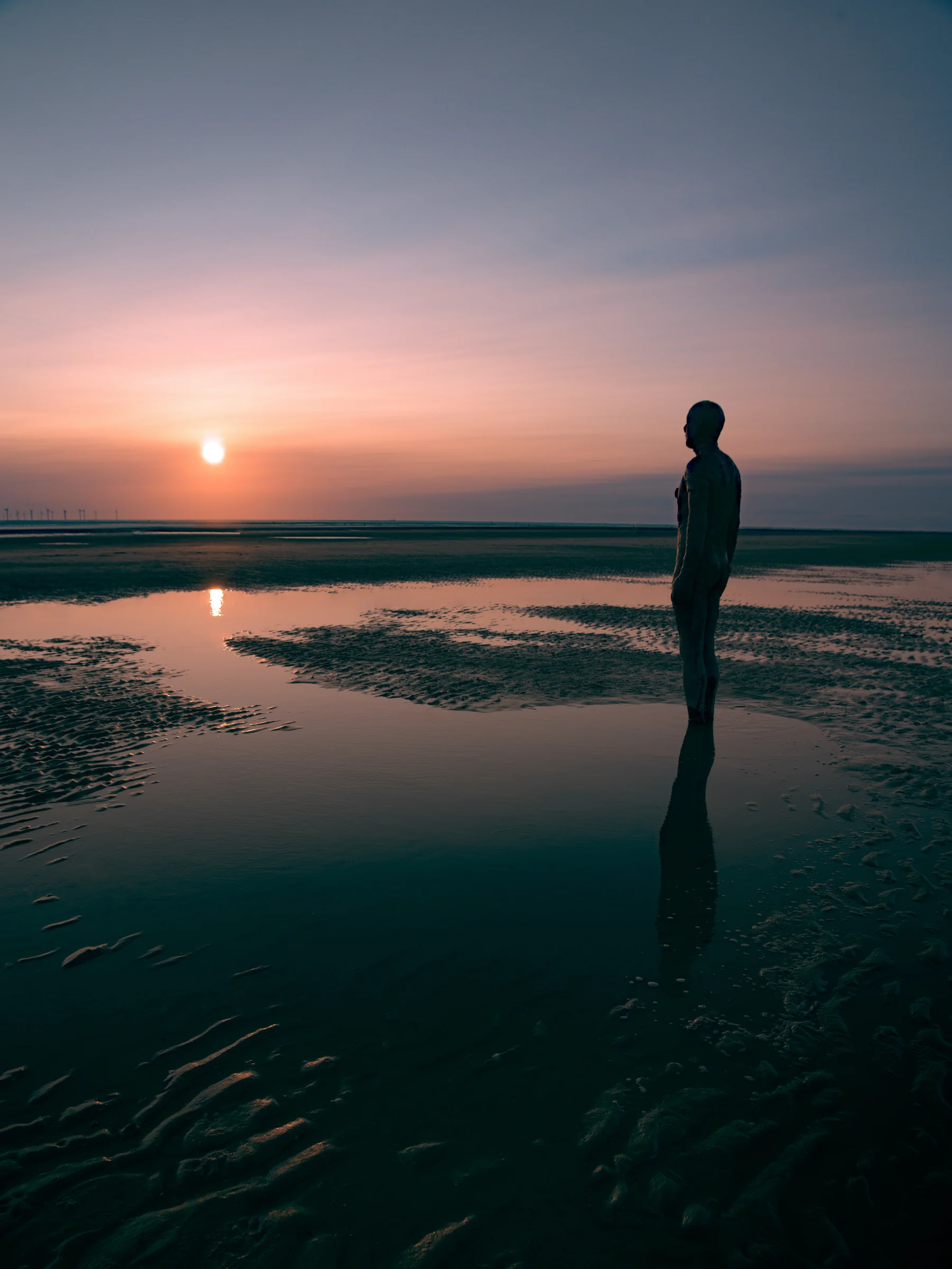 There's a strong chance this image contains the following subjects: water,  sea,  sunset,  dawn,  beach,  sun,  merseyside. The photographer has provided the following description: During sunset on one of the best beaches in the UK! Photographer_name: Chris Michael. Title: Crosby Beach. The photographer has provided the following description: During sunset on one of the best beaches in the UK! Make: canon. Model: EOS R. Technical: 16mm. Published: 2025-09-07 22:12:29