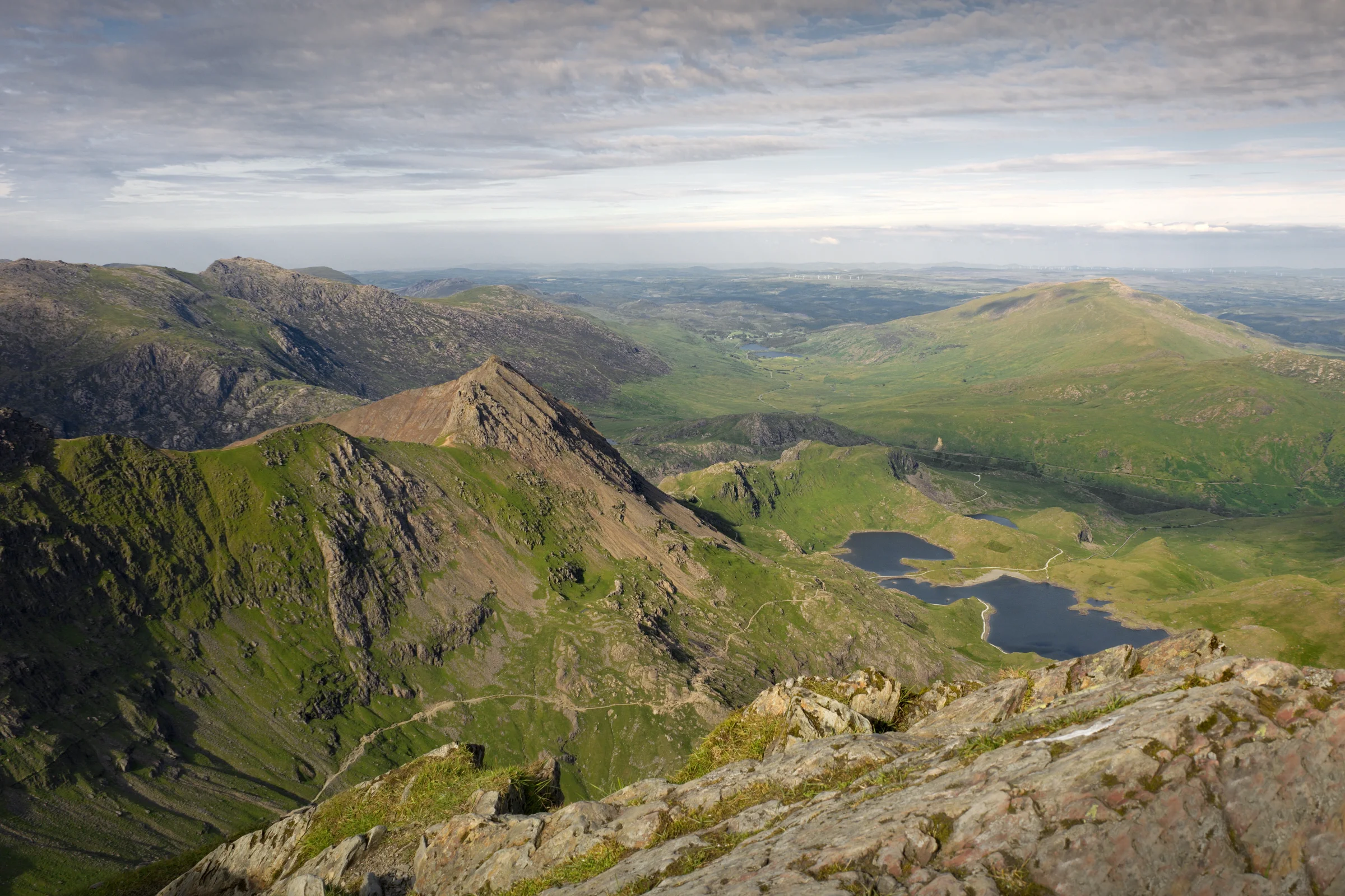 There's a strong chance this image contains the following subjects: sky,  landscape,  travel,  nature,  valley,  wales,  snowdonia,  eryri,  eryrinationalpark,  nationalpark,  snowdon. The photographer has provided the following description: This is a 12-shot image of the east facing view from the summit of Snowdon in Wales. It's a long walk up, but for those unable to hike you can always pay to take the Snowdon Mountain Railway to the summit. Well worth a visit. Photographer_name: Chris Michael. Title: Snowdon Summit. The photographer has provided the following description: This is a 12-shot image of the east facing view from the summit of Snowdon in Wales. It's a long walk up, but for those unable to hike you can always pay to take the Snowdon Mountain Railway to the summit. Well worth a visit. Make: fujifilm. Model: X-T5. Technical: 16-80mm. Published: 2025-09-09 16:05:44