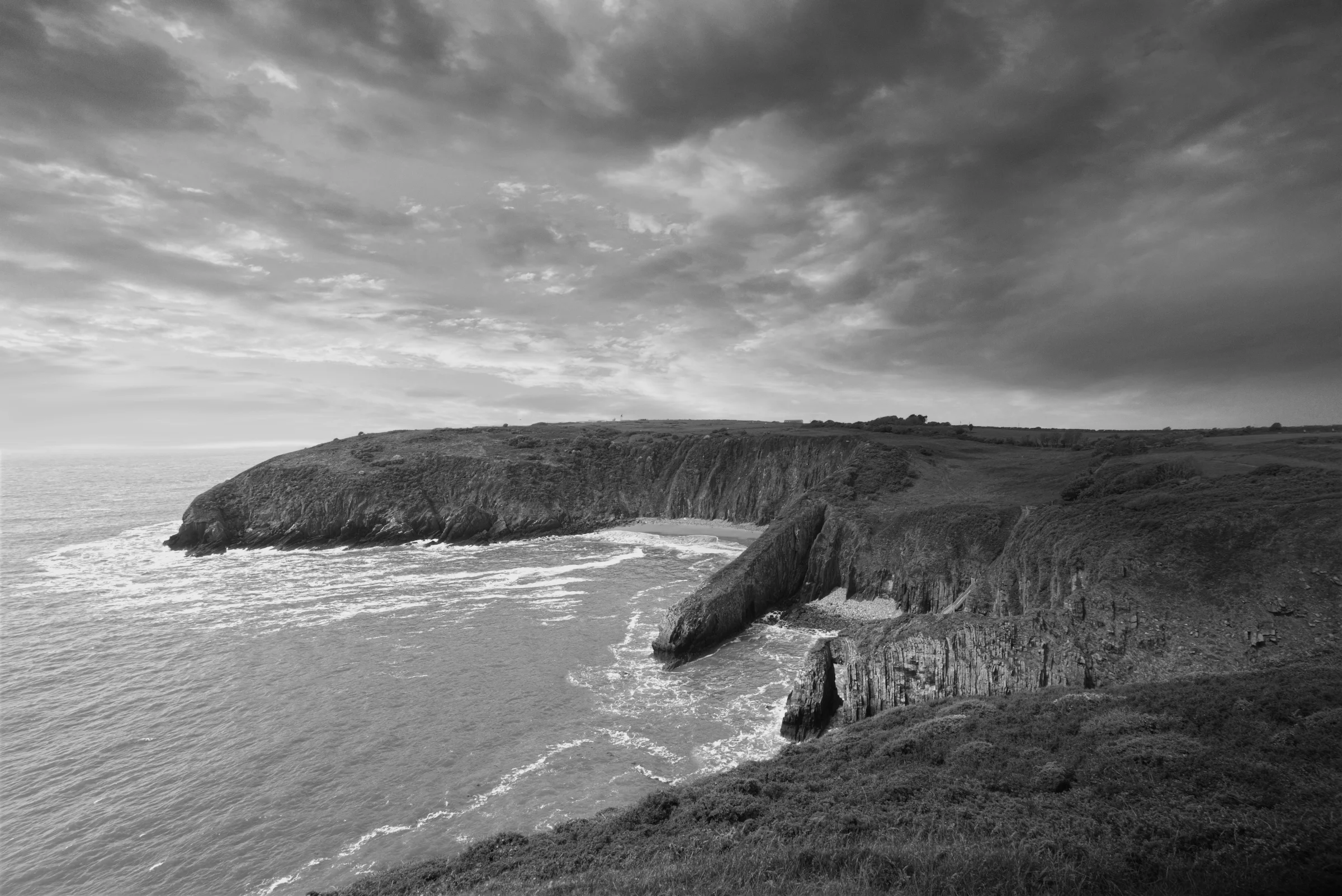 There's a strong chance this image contains the following subjects: monochrome,  water,  landscape,  sea,  beach,  ocean,  seashore,  blackandwhite,  seascape,  wales. The photographer has provided the following description: In South Wales, you'll find this hidden beauty...Skrinkle Haven Beach. Photographer_name: Chris Michael. Title: Skrinkle Haven. The photographer has provided the following description: In South Wales, you'll find this hidden beauty...Skrinkle Haven Beach. Make: fujifilm. Model: X-T5. Technical: 16-80mm. Published: 2025-09-09 13:44:15