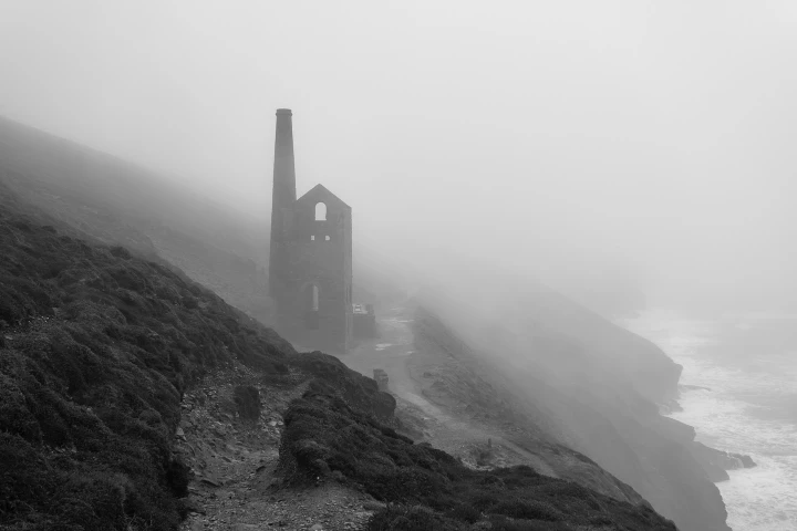 There's a strong chance this image contains the following subjects: architecture,  monochrome,  water,  landscape,  mist,  sea. FOTO has this to say about the photograph: A stunning black-and-white photograph of Wheal Coates, Cornwall, where swirling fog weaves through the rugged cliffs, adding haunting depth and atmosphere. Below, powerful waves crash against jagged rocks, creating a dramatic contrast that captures the wild, untamed beauty of the coastline. Source: https://www.instagram.com/paint_nothing/ Photographer_name: Phil. Title: Wheal Coates in the mist. FOTO has this to say about the photograph: A stunning black-and-white photograph of Wheal Coates, Cornwall, where swirling fog weaves through the rugged cliffs, adding haunting depth and atmosphere. Below, powerful waves crash against jagged rocks, creating a dramatic contrast that captures the wild, untamed beauty of the coastline. Published: 2025-06-15 12:07:52